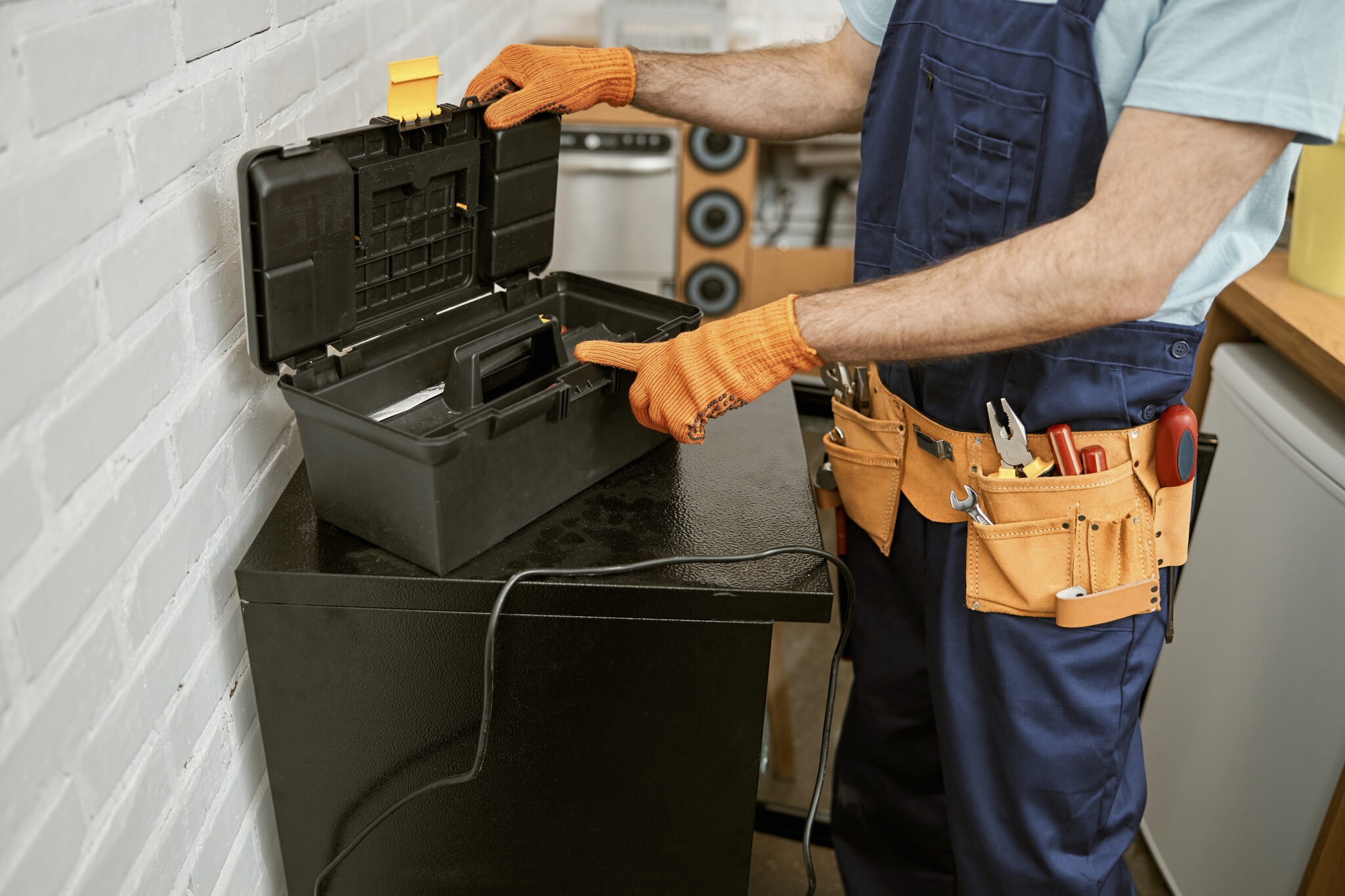 Close up of repairmen wearing work overalls with tool belt while checking plastic container with instruments