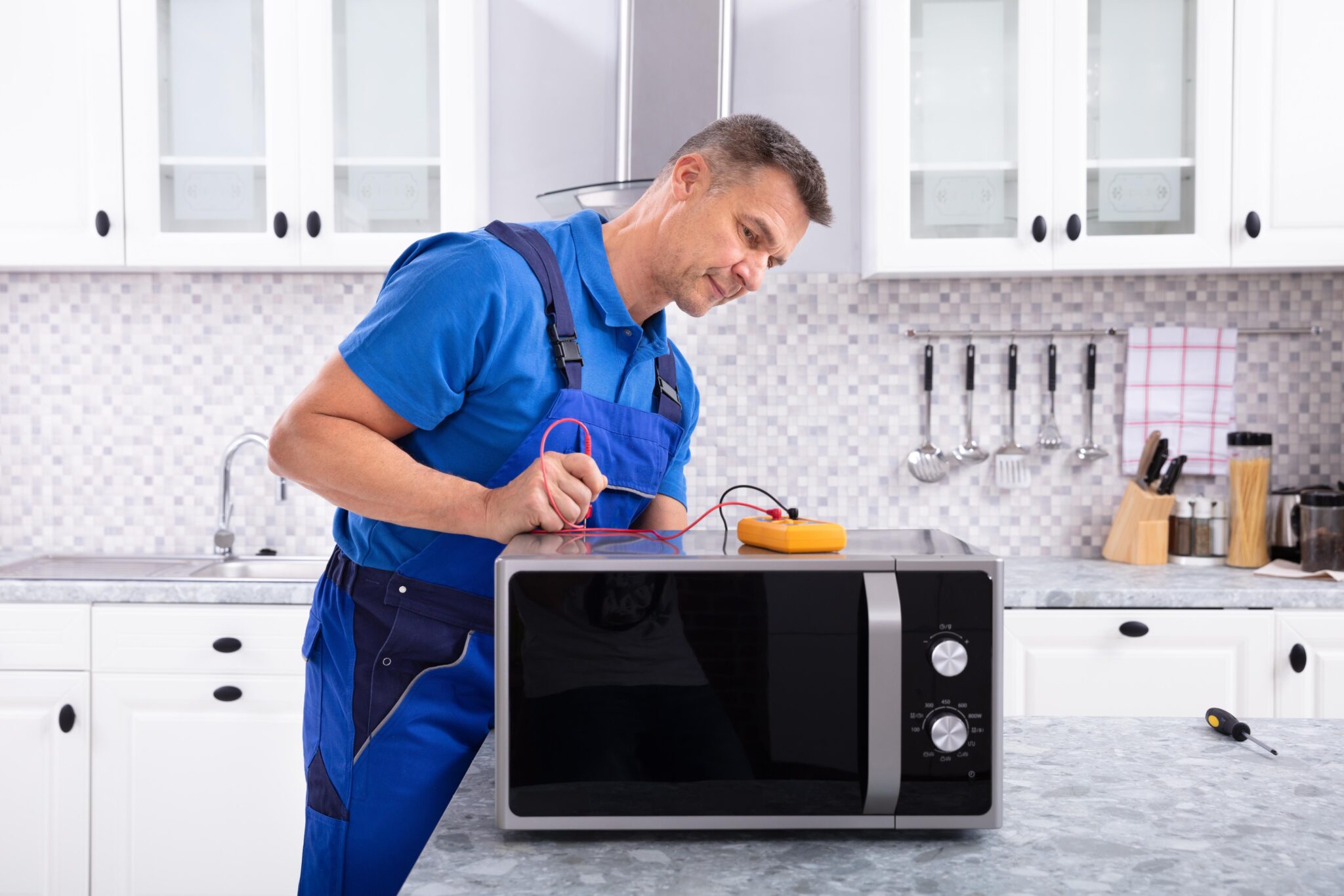 Mature Handyman Repairing Microwave Oven